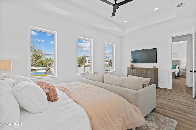 bedroom with dark wood-type flooring, ceiling fan, and a raised ceiling