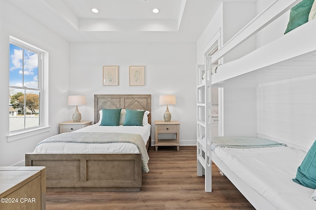 bedroom with dark hardwood / wood-style floors and a tray ceiling