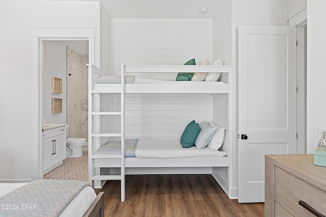 bedroom with connected bathroom and dark wood-type flooring