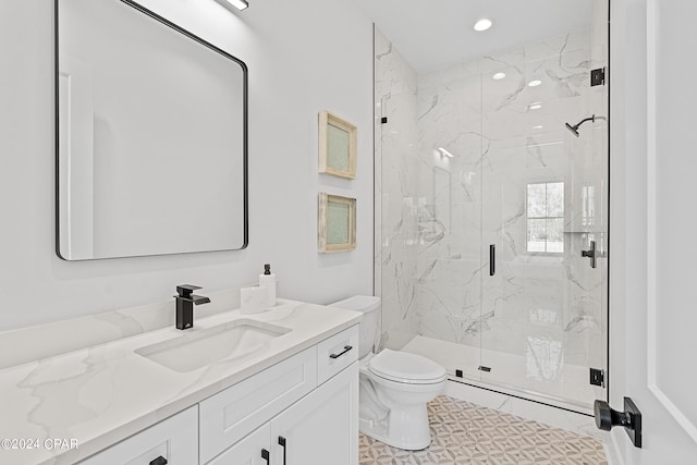 bathroom with vanity, a shower with door, and toilet