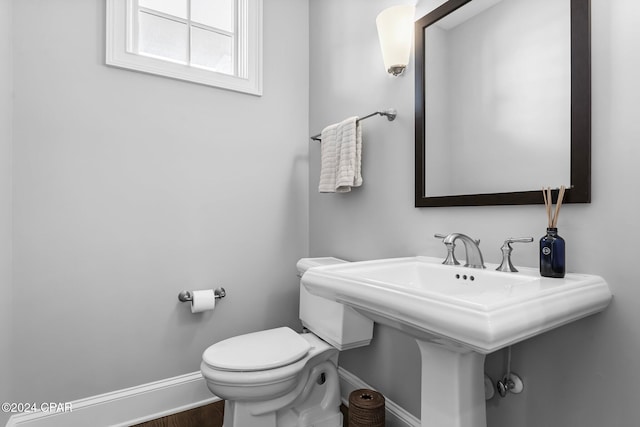 bathroom featuring baseboards, toilet, wood finished floors, and a sink