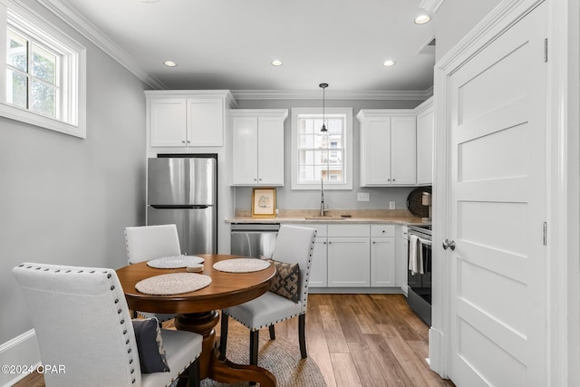 kitchen with ornamental molding, stainless steel appliances, white cabinetry, and a sink