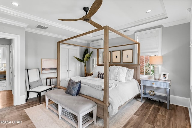 bedroom featuring wood finished floors, visible vents, baseboards, and ornamental molding