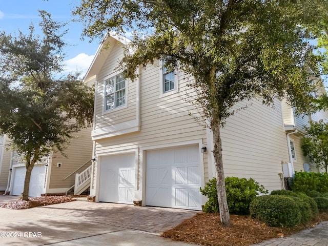 view of side of home featuring an attached garage and decorative driveway