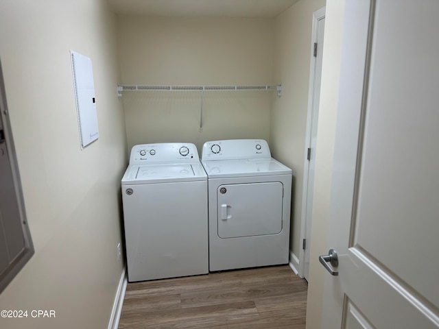 clothes washing area featuring light wood-type flooring, separate washer and dryer, and electric panel