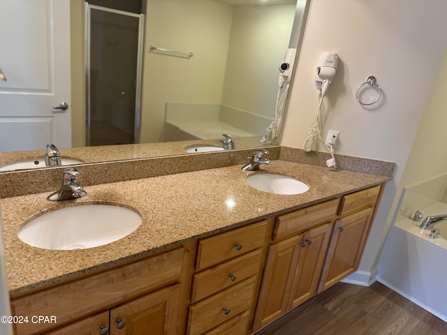 bathroom featuring vanity, wood-type flooring, and a bath