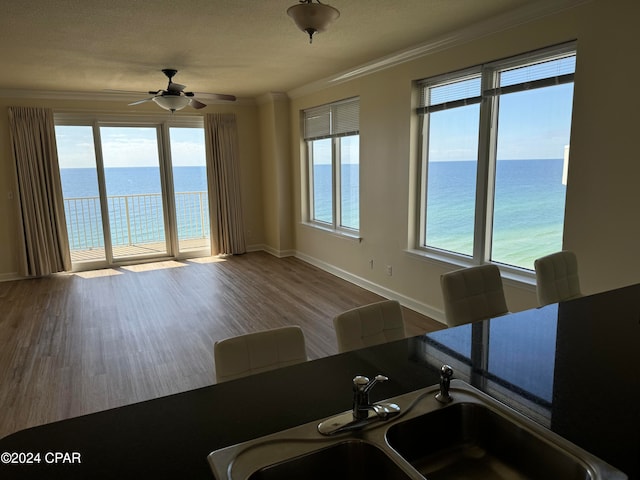 unfurnished dining area featuring sink, a water view, and hardwood / wood-style floors