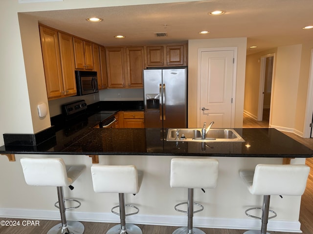 kitchen with a breakfast bar area, kitchen peninsula, sink, and black appliances