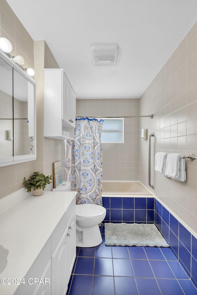 full bathroom with toilet, tile walls, a textured ceiling, shower / bath combination with curtain, and tile patterned flooring