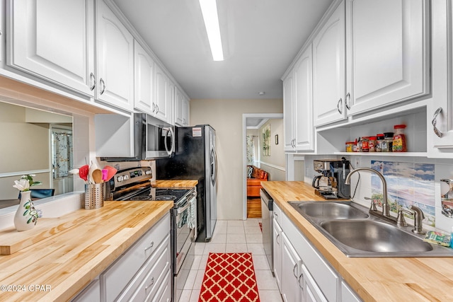 kitchen featuring appliances with stainless steel finishes, sink, white cabinets, and wood counters