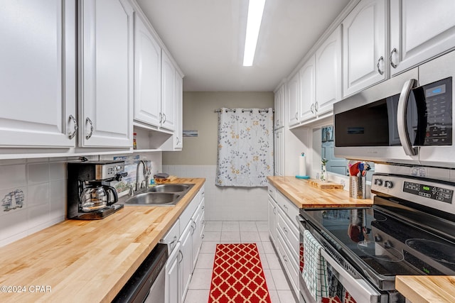 kitchen featuring butcher block countertops, white cabinetry, sink, light tile patterned floors, and stainless steel appliances