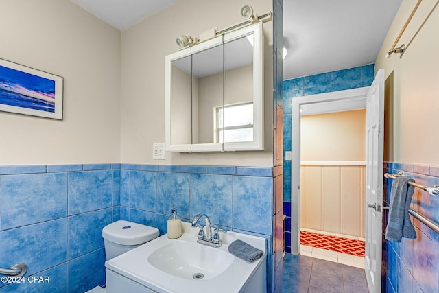 bathroom with tile patterned flooring, vanity, tile walls, and toilet