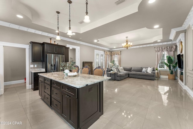 kitchen featuring pendant lighting, a kitchen island, stainless steel refrigerator with ice dispenser, and a tray ceiling