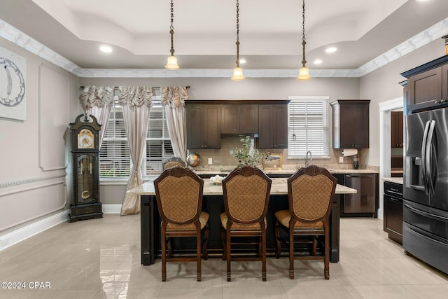 kitchen featuring dark brown cabinetry, stainless steel appliances, a tray ceiling, a center island, and hanging light fixtures