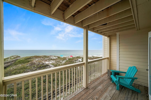 wooden deck featuring a beach view and a water view