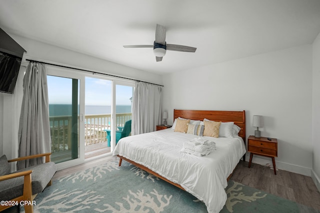 bedroom featuring access to exterior, hardwood / wood-style floors, a water view, and ceiling fan