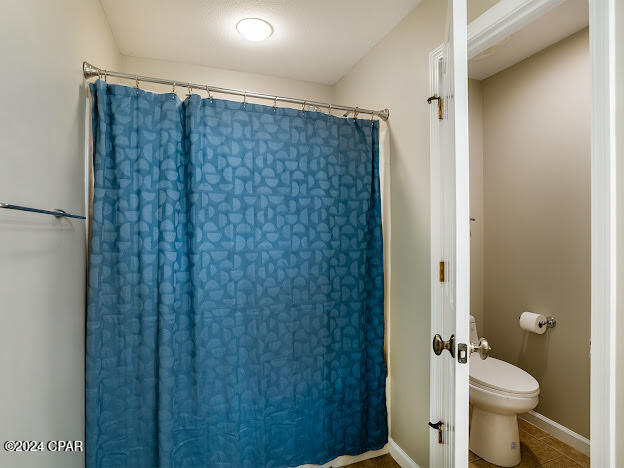 bathroom featuring tile patterned floors, curtained shower, and toilet