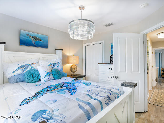 bedroom featuring a closet, light hardwood / wood-style floors, and an inviting chandelier