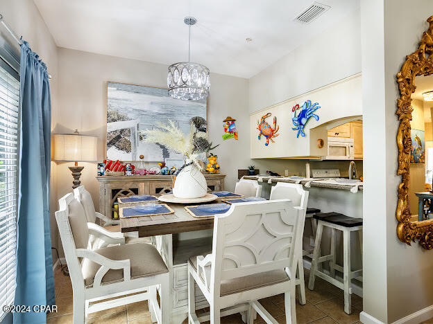 dining space with light tile patterned flooring and an inviting chandelier