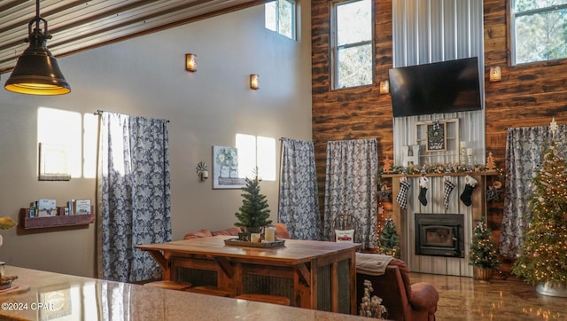 dining room with ornamental molding, a fireplace, wood walls, hardwood / wood-style floors, and a high ceiling