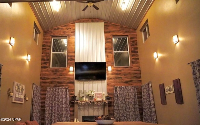 living room with wood walls, vaulted ceiling, a fireplace, and ceiling fan