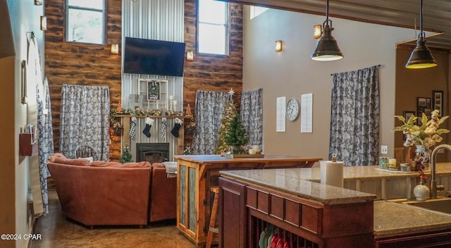 kitchen featuring ornamental molding, wood walls, hanging light fixtures, sink, and a tile fireplace