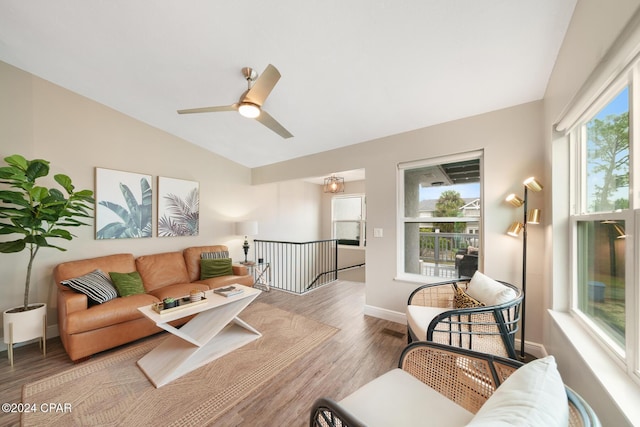 living area featuring a ceiling fan, vaulted ceiling, baseboards, and wood finished floors