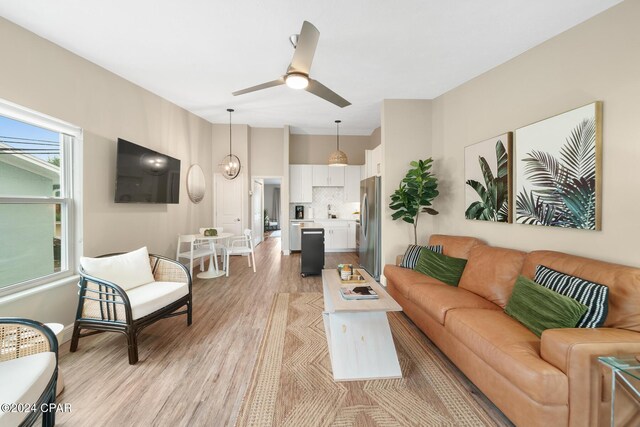 living room featuring light hardwood / wood-style floors, ceiling fan, and sink