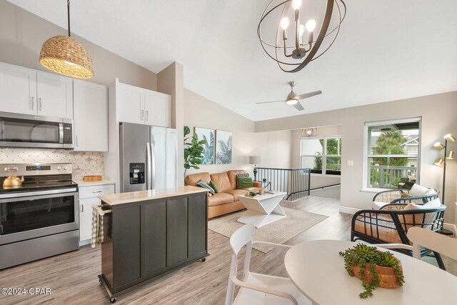 kitchen with lofted ceiling, white cabinetry, stainless steel appliances, and light hardwood / wood-style flooring