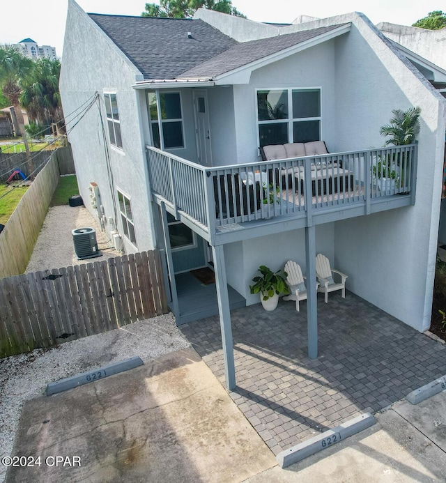 rear view of property featuring stucco siding, a patio area, a balcony, and roof with shingles