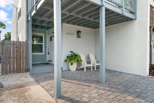 view of patio with fence and a balcony