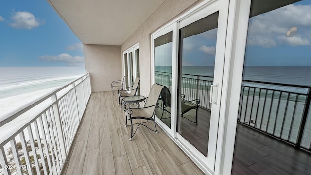 balcony with a water view and a view of the beach