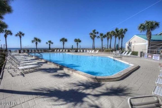 view of swimming pool featuring a water view and a patio area