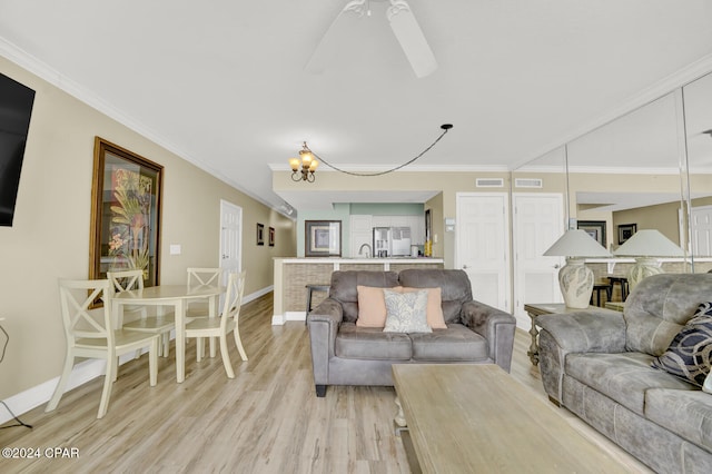 living room with ceiling fan with notable chandelier, light wood-type flooring, and crown molding