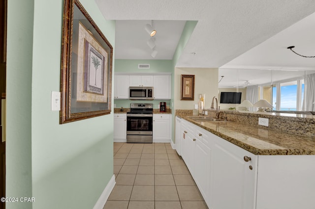 kitchen featuring stainless steel appliances, stone counters, white cabinets, and sink