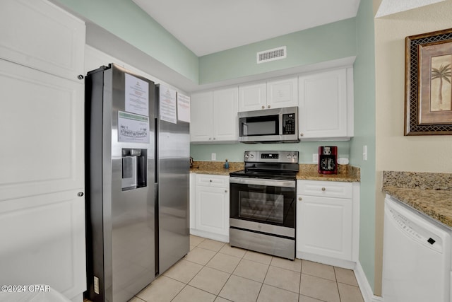 kitchen with white cabinets, light tile patterned floors, light stone counters, and appliances with stainless steel finishes