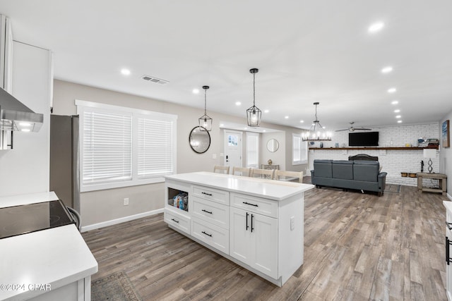 kitchen with a kitchen island, brick wall, white cabinets, and decorative light fixtures