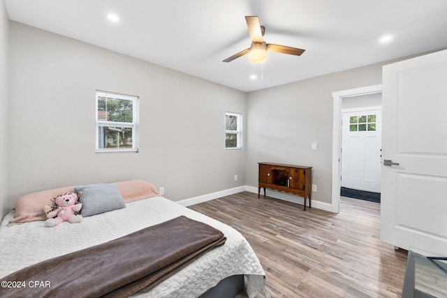 bedroom featuring ceiling fan, light hardwood / wood-style floors, and multiple windows