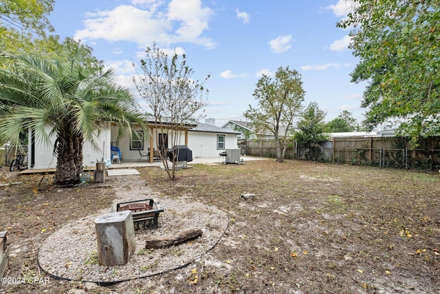 view of yard with central AC, a patio area, and an outdoor fire pit