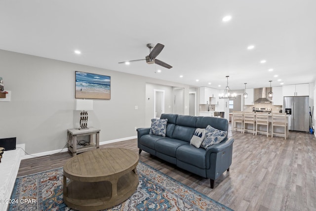 living room featuring sink, light hardwood / wood-style floors, and ceiling fan with notable chandelier