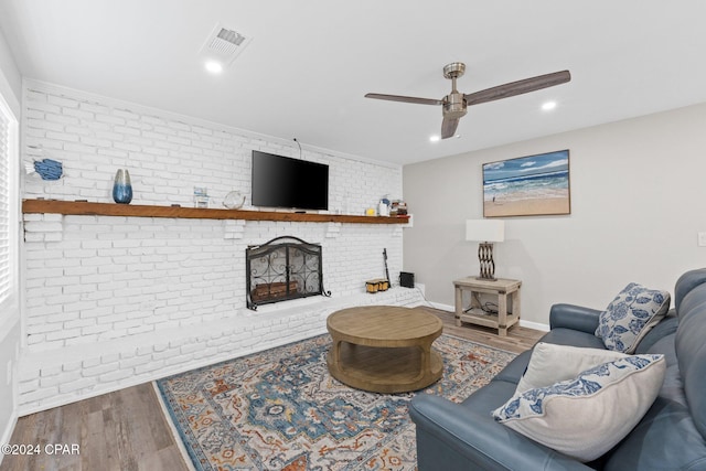 living room with wood-type flooring, brick wall, a fireplace, and ceiling fan