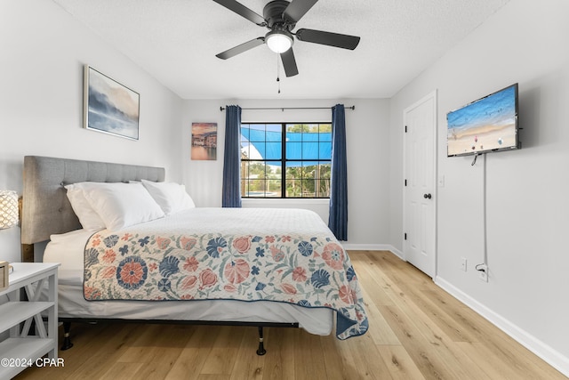 bedroom with ceiling fan, a textured ceiling, and light hardwood / wood-style floors