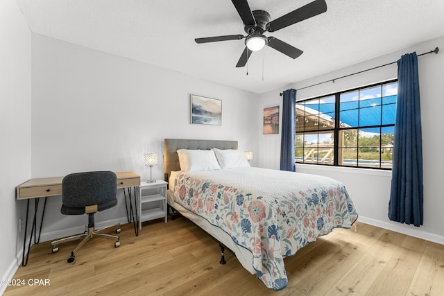 bedroom with ceiling fan, light hardwood / wood-style floors, and a textured ceiling