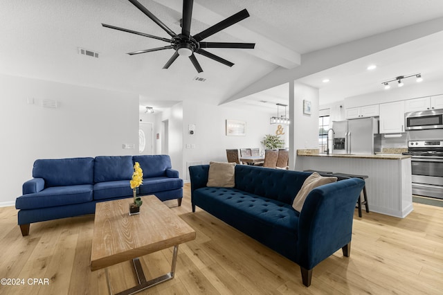 living room with ceiling fan with notable chandelier, a textured ceiling, light hardwood / wood-style flooring, and lofted ceiling with beams