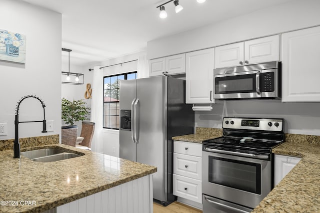 kitchen with stainless steel appliances, pendant lighting, white cabinets, light stone counters, and sink