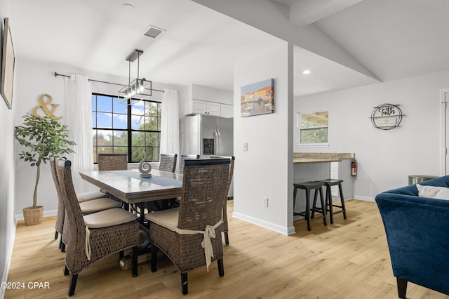 dining room with vaulted ceiling with beams and light wood-type flooring