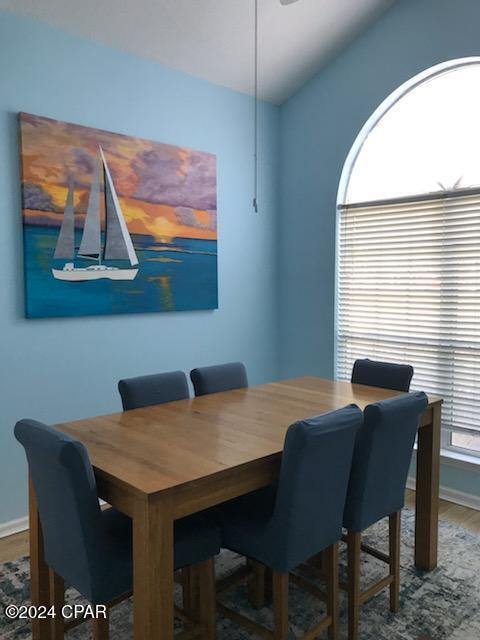 dining area featuring wood-type flooring and vaulted ceiling