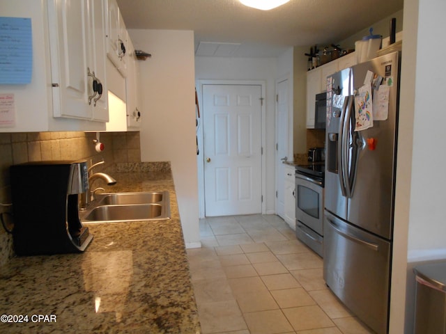 kitchen featuring sink, white cabinetry, light tile patterned floors, stainless steel appliances, and decorative backsplash