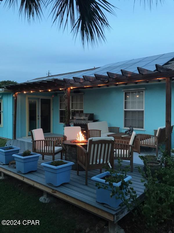 deck at dusk with an outdoor living space with a fire pit and french doors