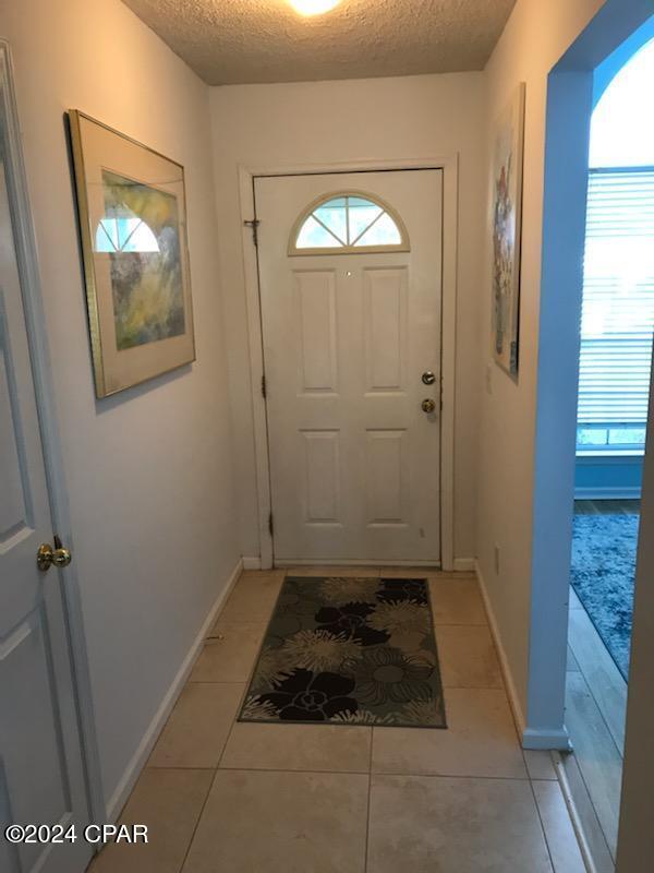 doorway to outside featuring light tile patterned floors, a wealth of natural light, and a textured ceiling